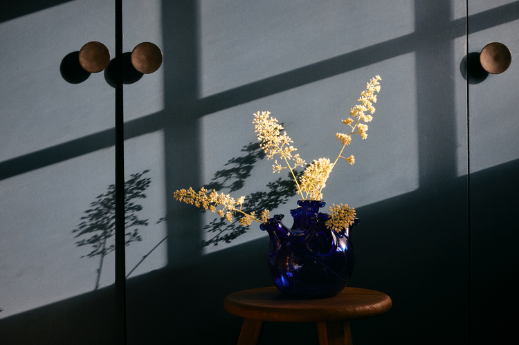 glass vase with flowers on stool with dapper light