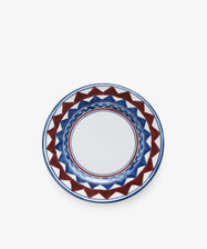 The Luca Small Plate, Set of 4, features round ceramic plates hand-painted with a geometric blue and red pattern around the rim on a white background, inspired by classic PORTA-designed plates.