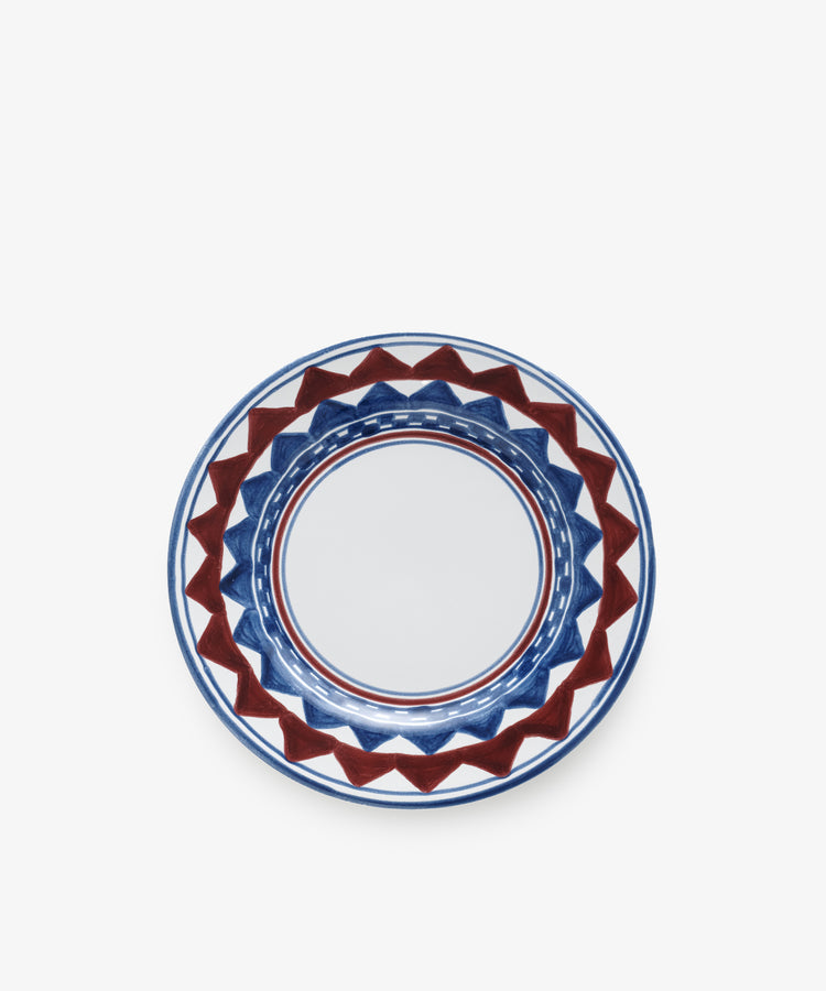The Luca Small Plate, Set of 4, features round ceramic plates hand-painted with a geometric blue and red pattern around the rim on a white background, inspired by classic PORTA-designed plates.