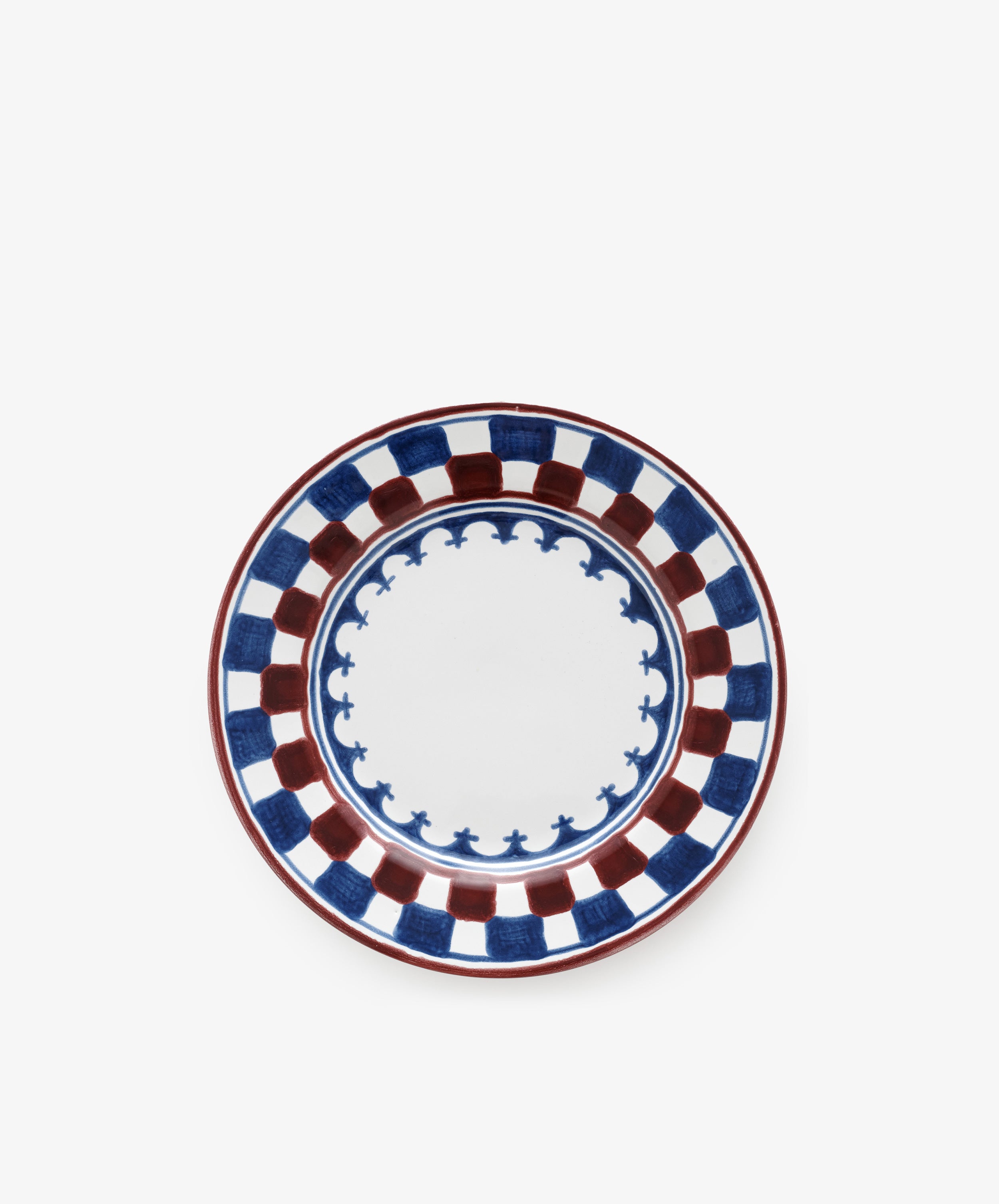 The Luca Small Plate, Set of 4, features a hand-painted blue and red checkerboard rim with a scalloped blue inner border on white, inspired by traditional motifs.