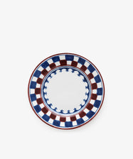 The Luca Small Plate, Set of 4, features a hand-painted blue and red checkerboard rim with a scalloped blue inner border on white, inspired by traditional motifs.
