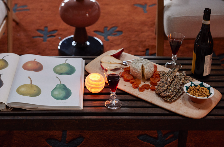 coffee table with cutting board and crackers cheese and nuts, red wine bottle with red wine in glasses