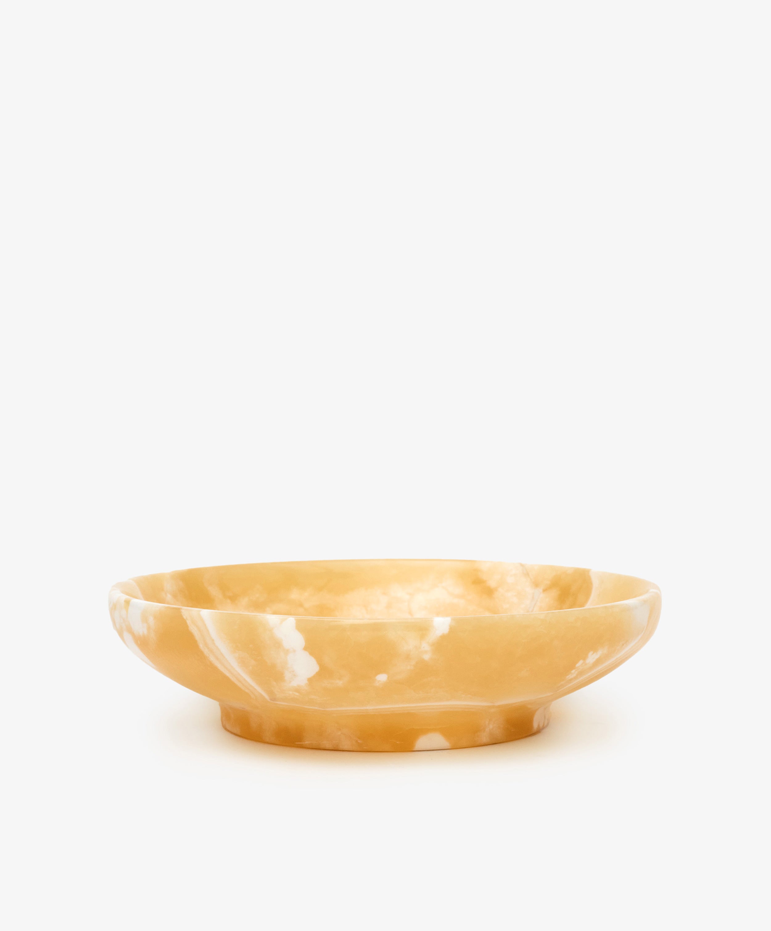 The Akila Decorative Bowl is a shallow, round Egyptian alabaster piece with amber color and white marbling, expertly handcrafted for unique home decor, shown against a plain white background.
