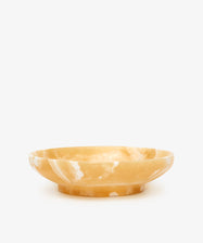 The Akila Decorative Bowl is a shallow, round Egyptian alabaster piece with amber color and white marbling, expertly handcrafted for unique home decor, shown against a plain white background.