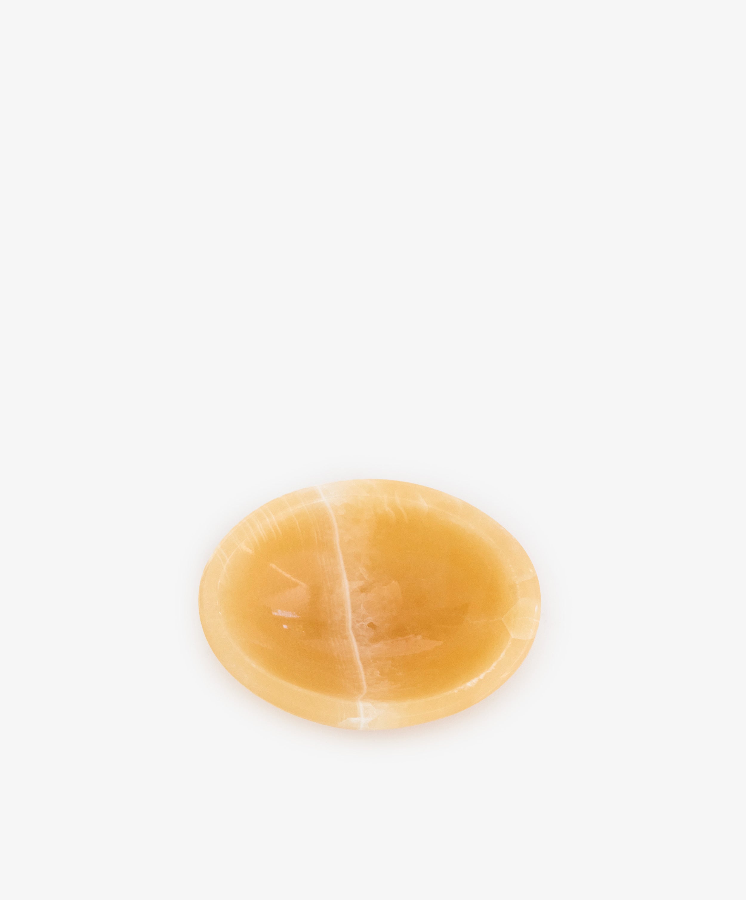 The Akila Catchall is a small, round, shallow bowl made of smooth, polished Egyptian Alabaster, handcrafted for subtle decorative accents and shown centered on a plain white background.