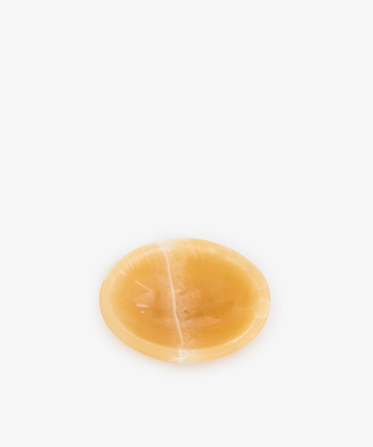 The Akila Catchall is a small, round, shallow bowl made of smooth, polished Egyptian Alabaster, handcrafted for subtle decorative accents and shown centered on a plain white background.