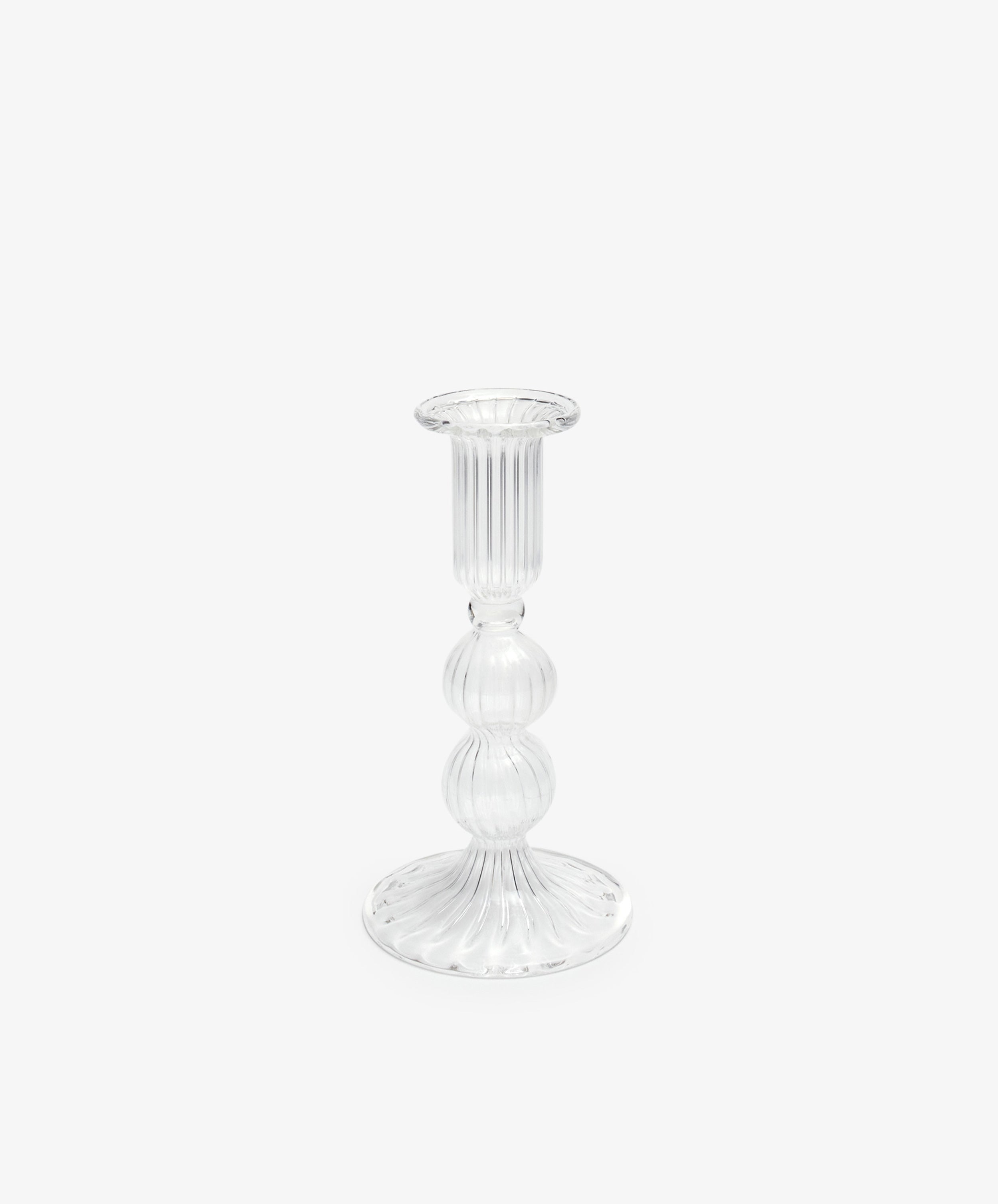 The Elsa Candleholder is a clear glass candlestick holder with a ribbed design, round base, and bulbous midsection, shown against a plain white background—ideal for elegant home decor.