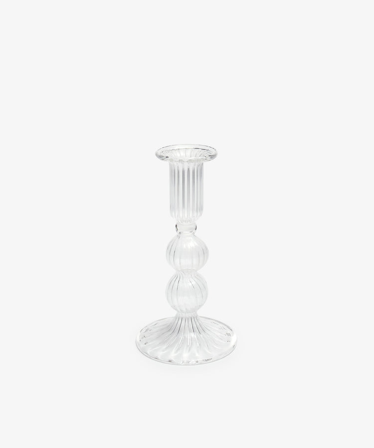 The Elsa Candleholder is a clear glass candlestick holder with a ribbed design, round base, and bulbous midsection, shown against a plain white background—ideal for elegant home decor.