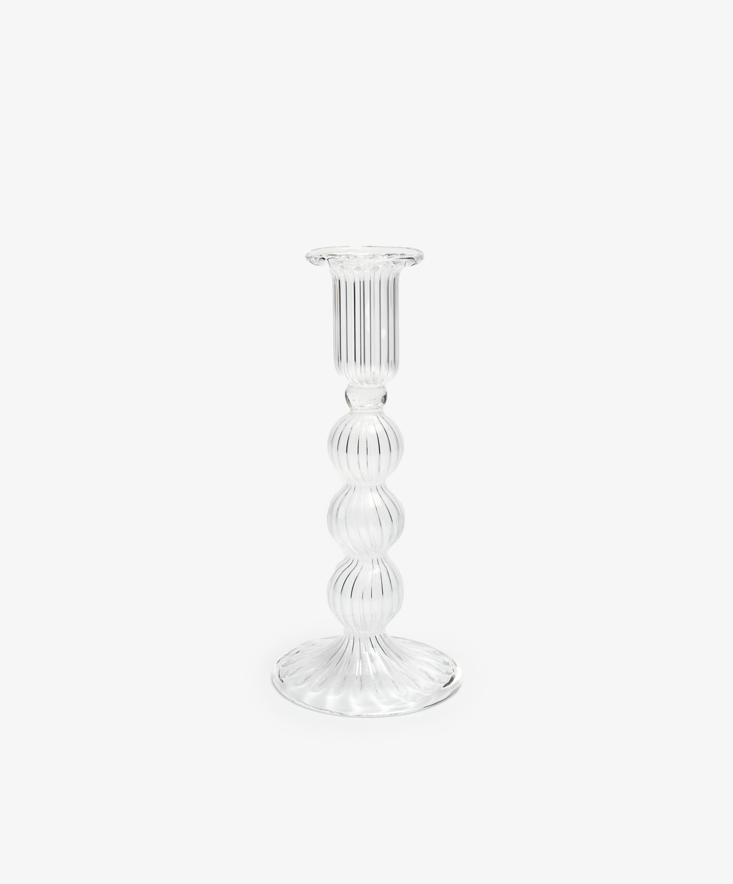 The Elsa Candleholder is a clear, hand-blown glass piece with a ribbed surface and round, tiered stem, expertly crafted by artisans and displayed against a plain white background.