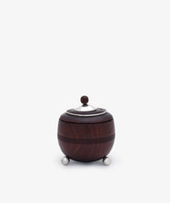 Curiosity Box 17: A round, dark African wood box with a metal lid and knob, set on three small metal legs from the Antje Weber collection—photographed against a plain white background.