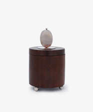 Curiosity Box 3: A round African wood box with a flat lid, featuring a circular frosted glass accent and metallic sphere top, supported by three metal feet—an elegant keepsake art box for your treasured items.