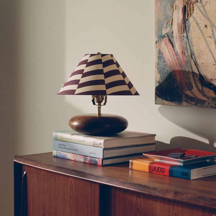 Table lamp with striped shade on stacked books on a wooden sideboard