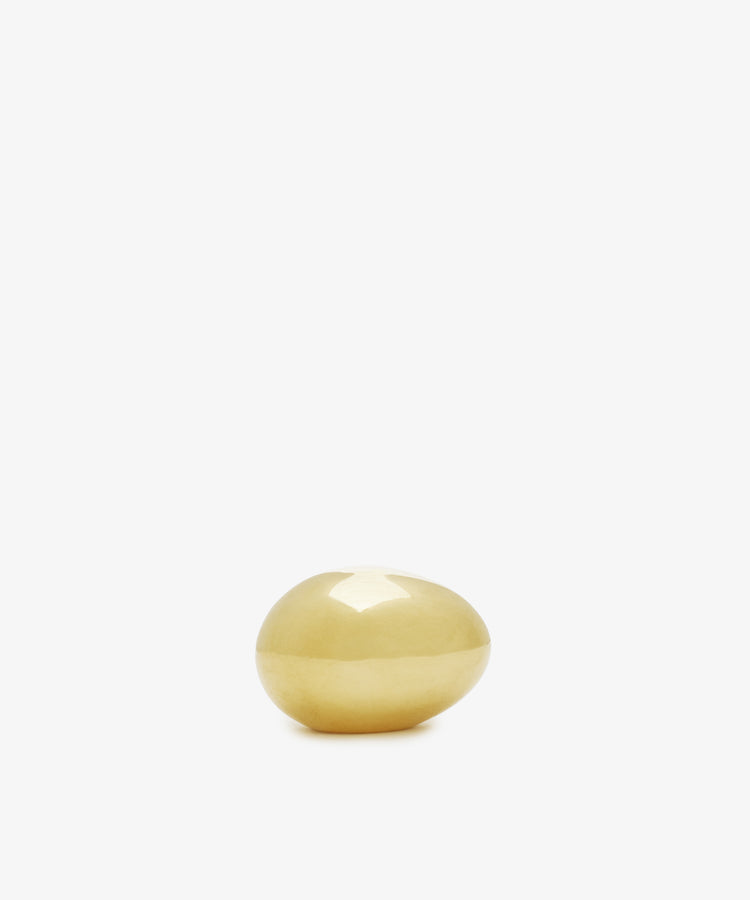 A single, smooth Egg Paperweight in yellow—resembling a brass egg by Auböck Vienna—is centered on a plain white background.