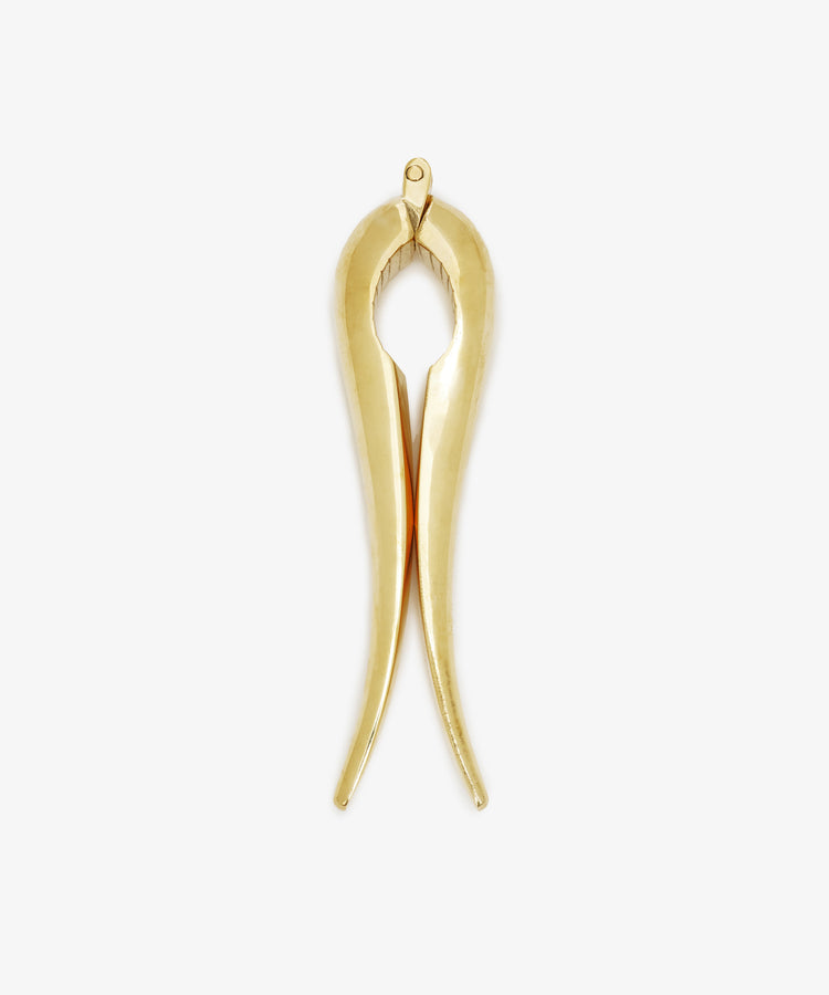 Gold-colored Nutcracker made of brass, shaped like tongs and set against a white background. This modern piece reflects the timeless elegance characteristic of the Auböck workshop’s design tradition.