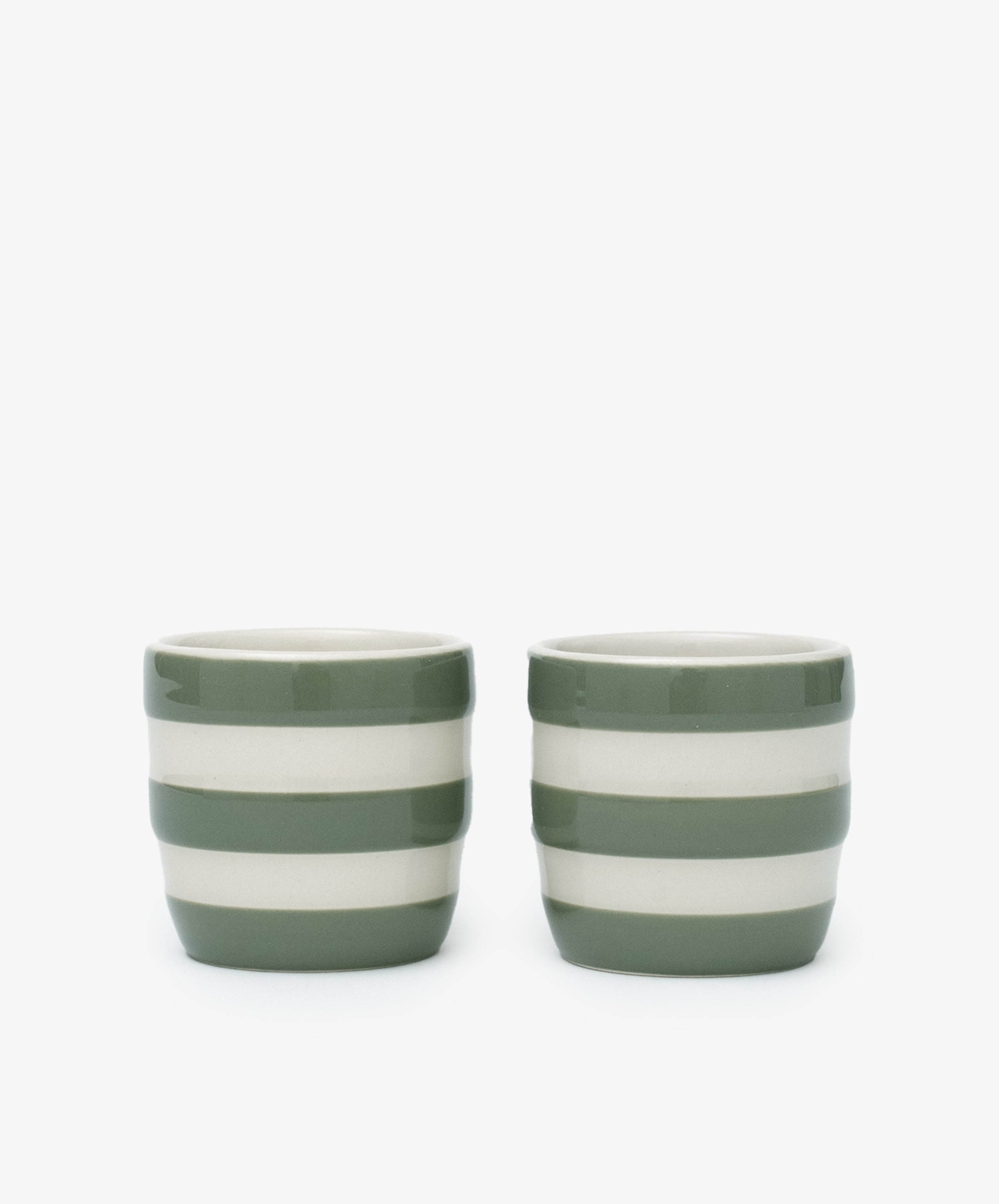 The Betty Egg Cup Set of 2 features ceramic cups with green and white horizontal stripes, inspired by UK West Country pottery, perfect for adding charm to your breakfast table.