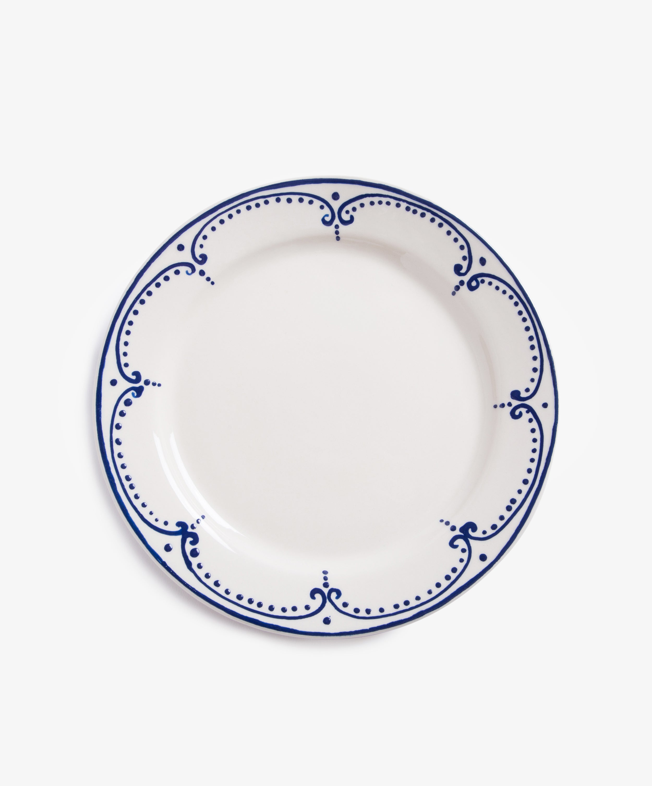 Arco Dinner Plate. Overhead view of white glazed ceramic plate with dark blue painted border design.
