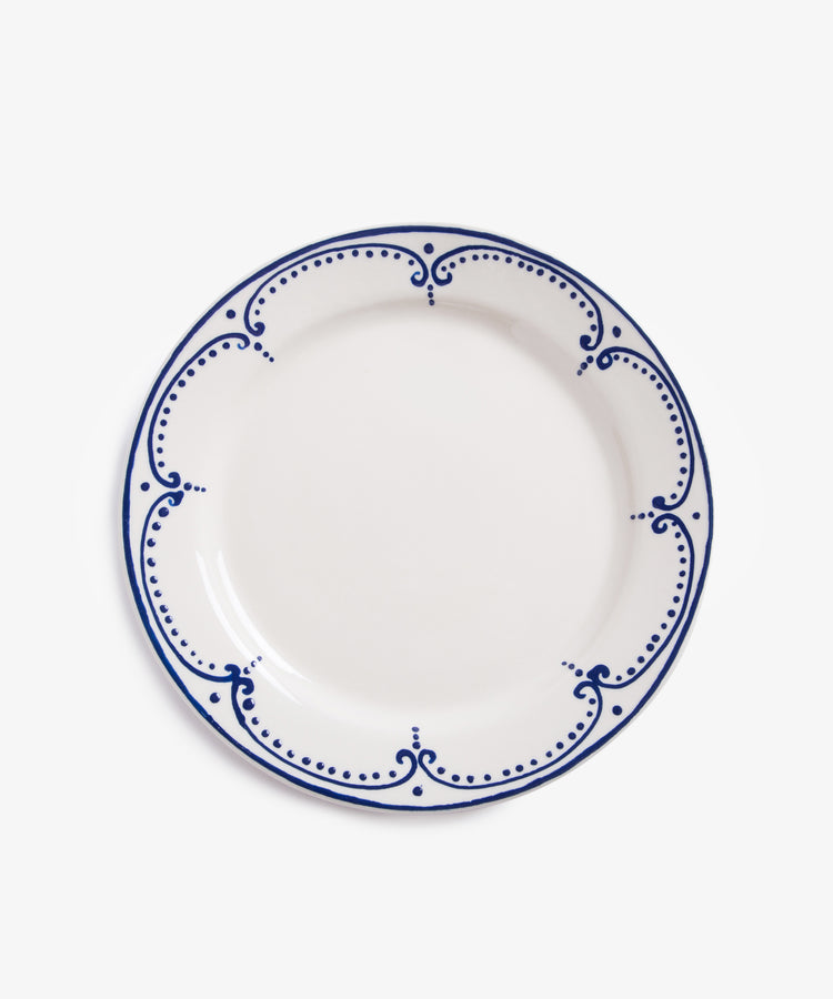 Arco Dinner Plate. Overhead view of white glazed ceramic plate with dark blue painted border design.