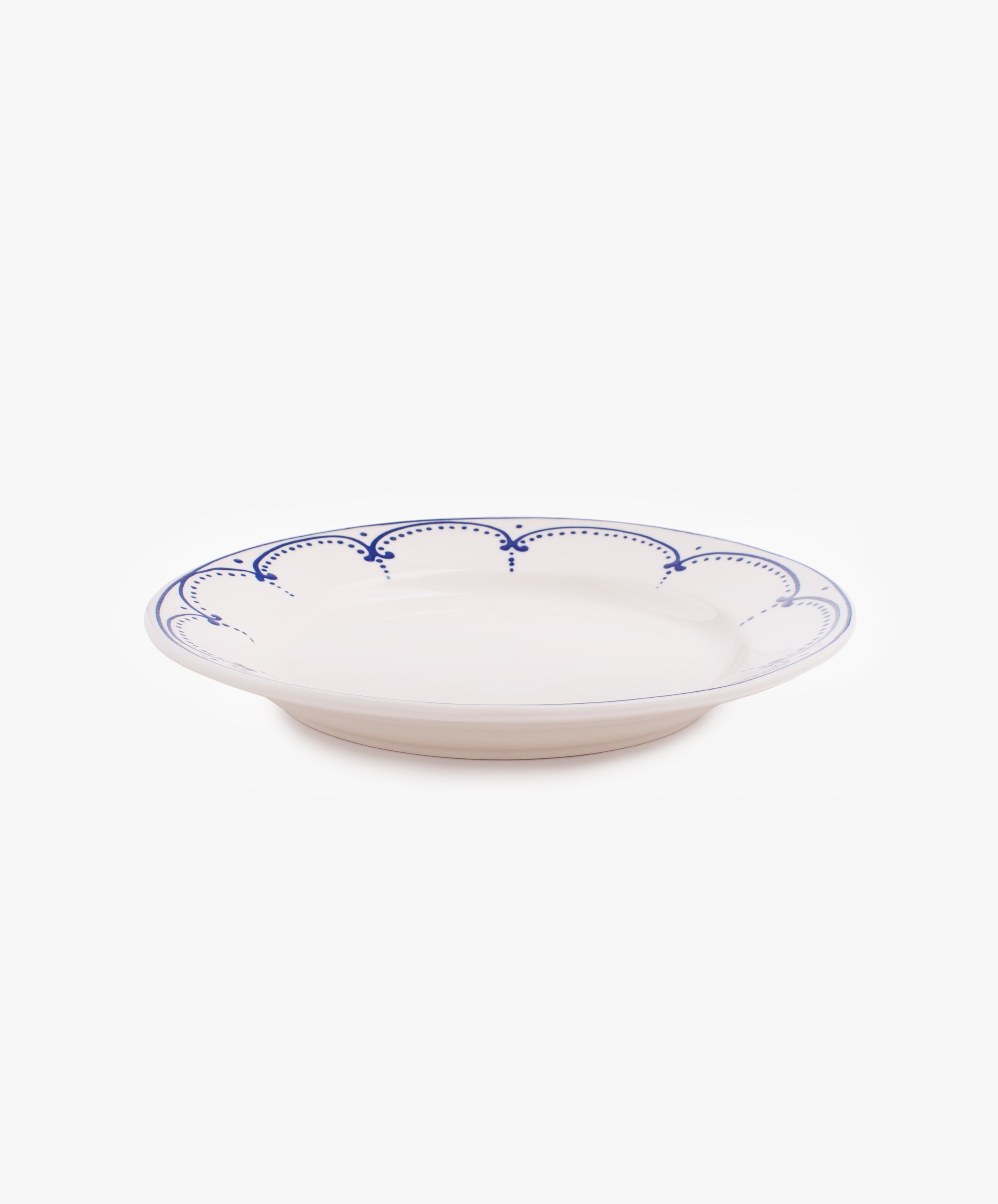 Side view of Arco dinner plate in white glazed ceramic with dark blue painted border design.
