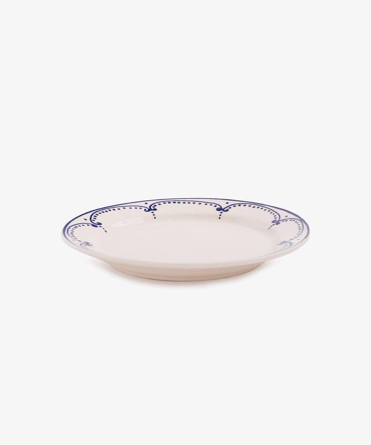 Side view of Arco small white glazed ceramic plate with dark blue handpainted border design.
