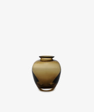 The Gem Bud Vase, a round hand-blown translucent brown glass piece with a narrow opening, crafted in the South of France, is centered on a plain white background.
