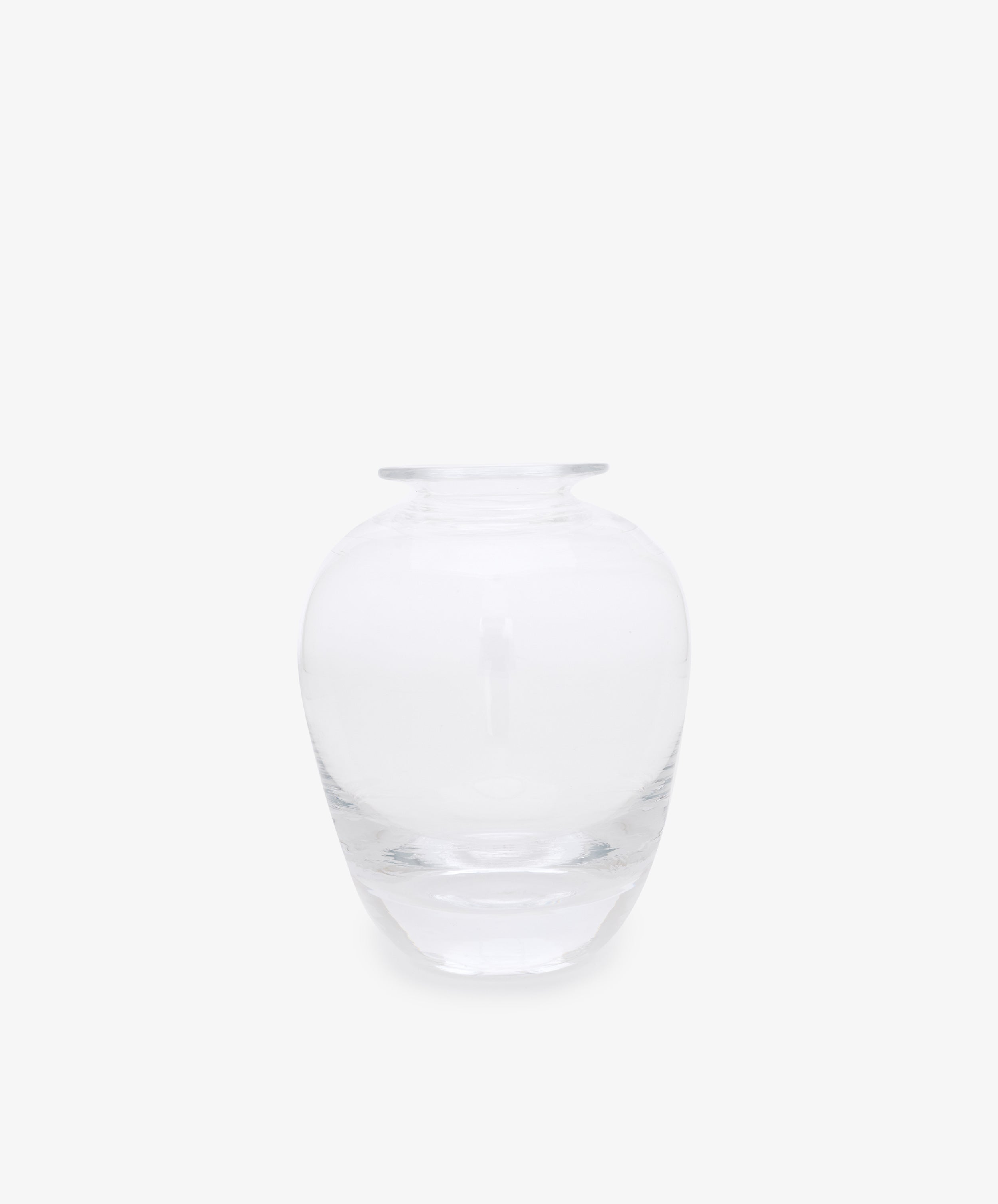 The Gem Bud Vase is a hand blown clear glass vase featuring a wide, round body and a short, narrow neck, shown against a plain white background.