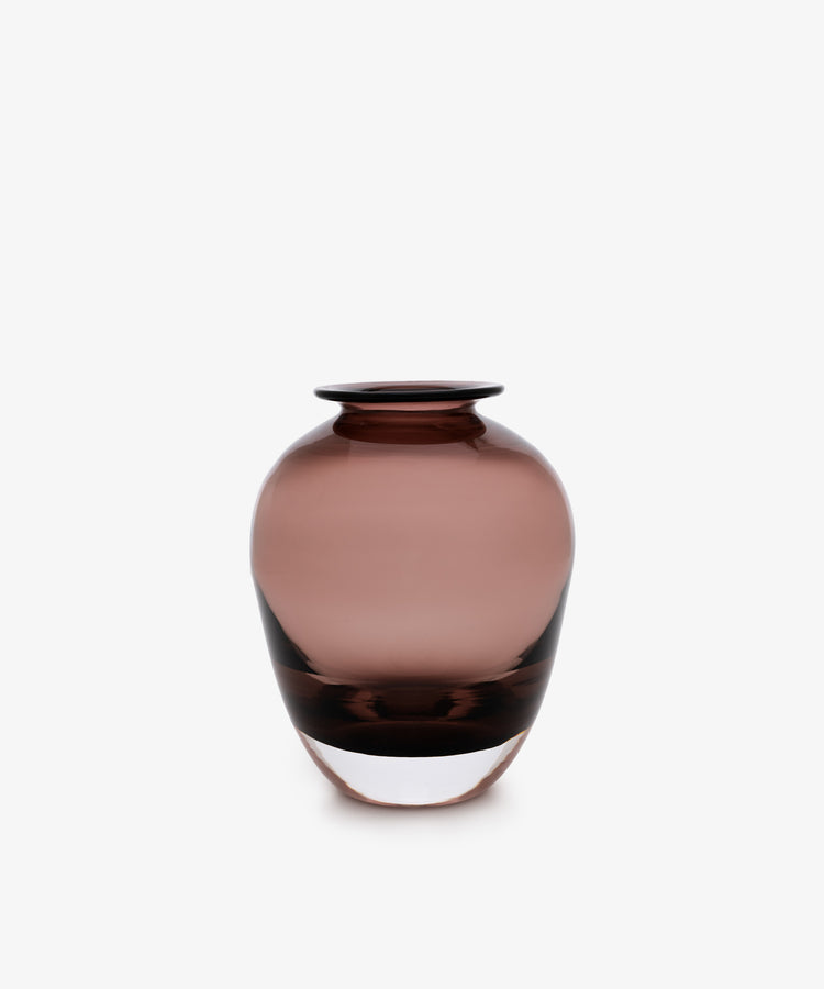 The Gem Bud Vase is a round, translucent mauve hand-blown glass vase with a narrow neck and wide body, ideal for displaying buds. Shown against a plain white background.