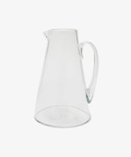 Handmade in the South of France, the Gemma Jug is a clear glass pitcher with crystal transparency, wide base, narrow top, small spout, and curved handle—beautifully photographed on a plain white background.