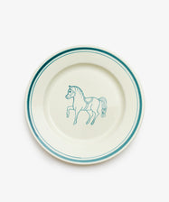 The Folk Dinner Plate, Horse is a white ceramic plate with teal rim accents and a hand-painted teal horse illustration at the center, expertly crafted by an Italian ceramist.