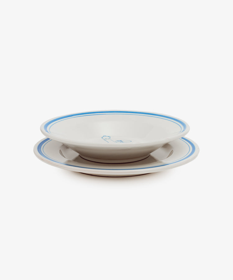 Two Folk Dinner Plate, Jester—white ceramic plates with blue rims and a small central blue design, hand-painted by Italian ceramists—are stacked together against a plain white background.