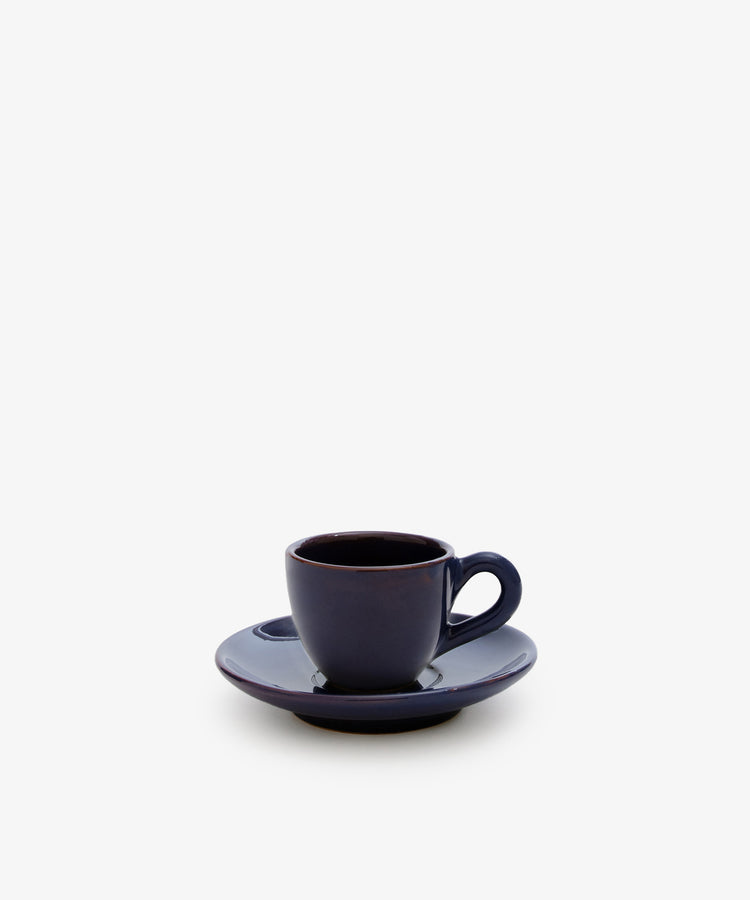 The Gio Espresso Set features a handmade dark blue ceramic mug with a matching saucer, displayed against a plain white background.