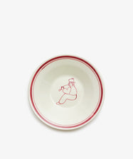 The Folk Pasta Bowl, Farmer, is a hand-glazed white ceramic bowl featuring two red rings near the rim and a central red illustration of a seated person playing a horn—an artistic addition to your tableware.