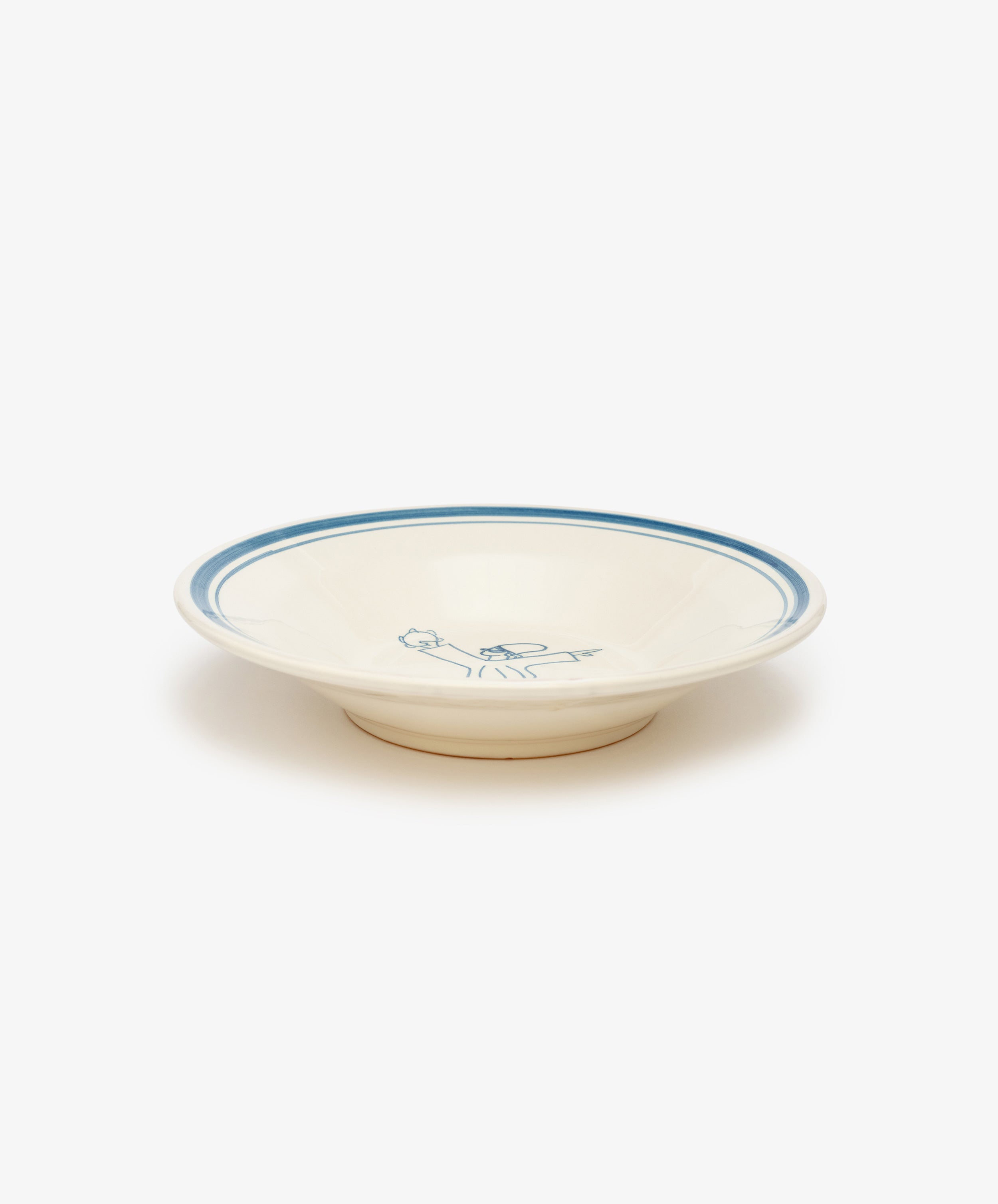 The Folk Pasta Bowl, Jester is a cream-colored ceramic bowl with a blue rim and a blue floral center design, hand-glazed by an Italian ceramist and photographed on a white background—a timeless tableware piece.