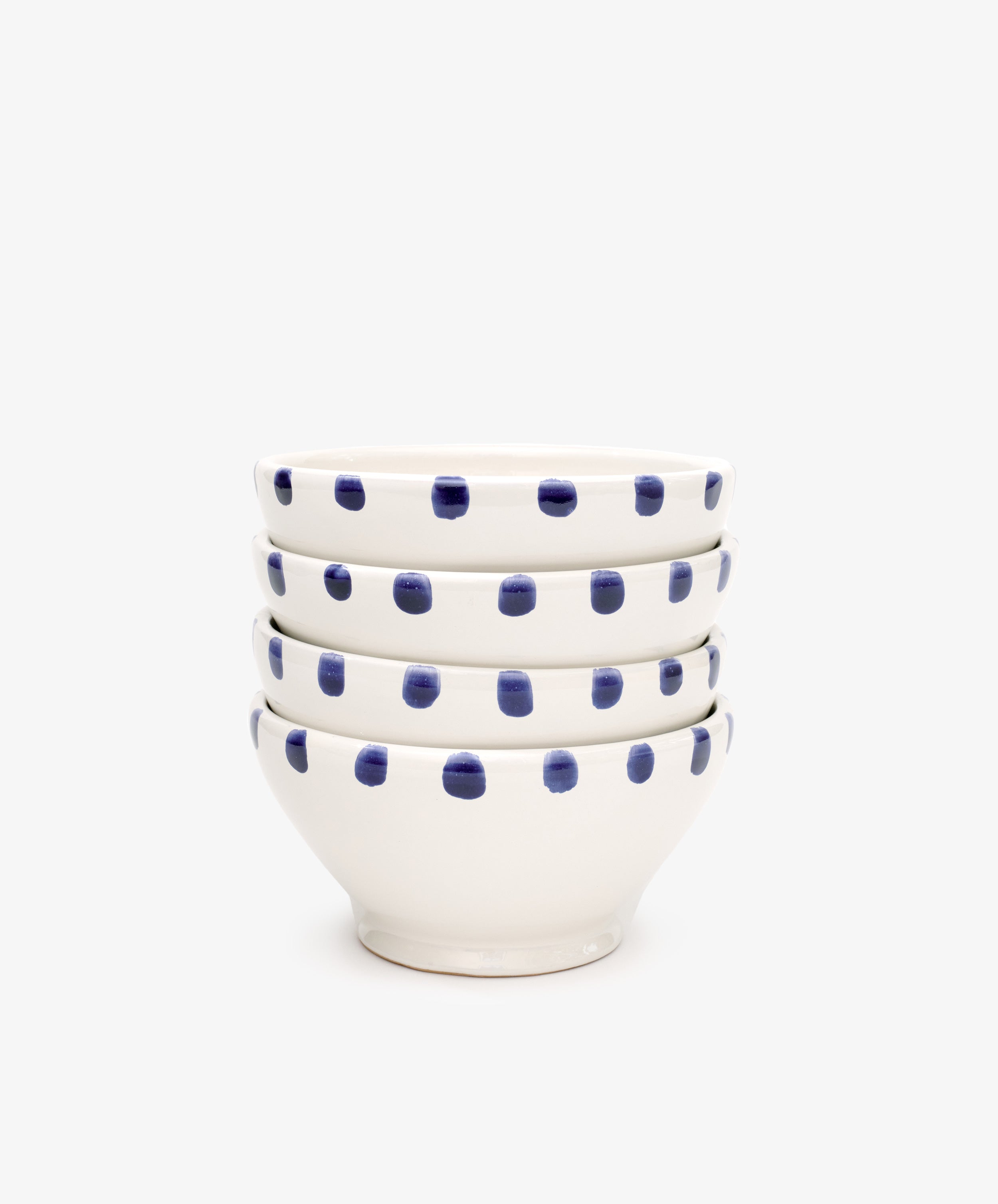 The Nina Bowl, Set of 4, features white ceramic bowls with blue polka dot patterns and a detailed dotted rim, shown stacked on a plain white background.