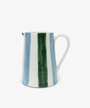 The Mina Jug is a hand-painted ceramic with a white base and vertical blue and green stripes, plus handle and spout—an artisanal accent perfect for your table setting.