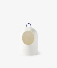 The Salt Pig is a white ceramic salt holder with a minimalist dome shape, circular opening, and a small blue handle on top, shown against a plain light background.