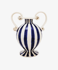 The Cyrene Bud Vase features hand-thrown craftsmanship, blue-and-white vertical stripes, and sculptural scroll handles, shown against a plain white background.