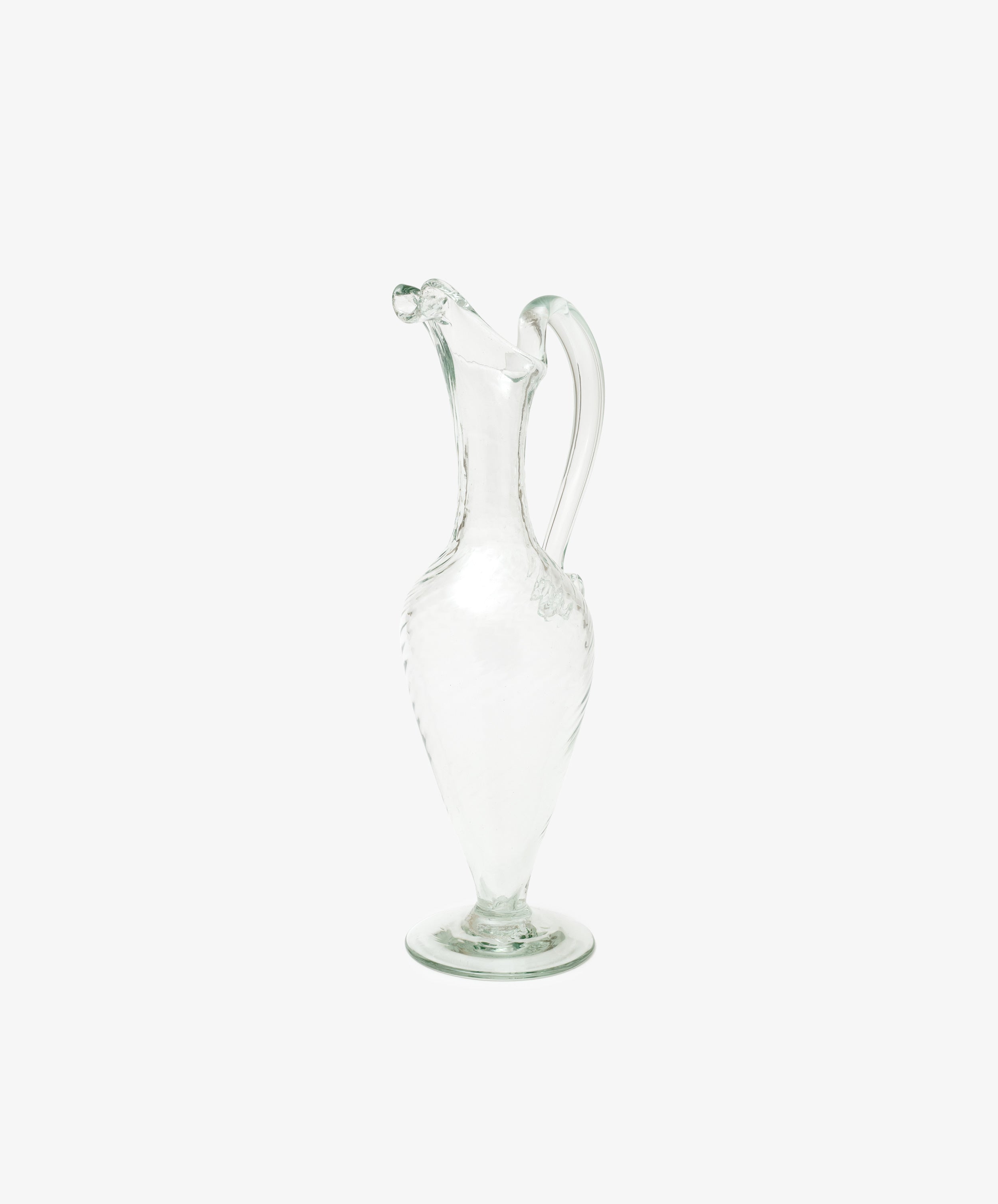 The Alba Vase, a hand-blown glass piece with a narrow neck, curved handle, and decorative spout, stands upright on a plain white background, highlighting its elegant and unique craftsmanship.