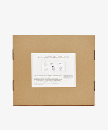 A brown cardboard box with a white label reading Capriccio Christmas Crackers, featuring product details and festive illustrations—ideal as holiday table crackers or Christmas party favors.