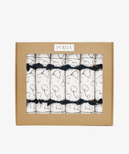 A box of six Capriccio Christmas Crackers featuring white wraps with black line art and navy ribbons, packaged in a labeled brown cardboard window box—ideal festive favors for your holiday party.