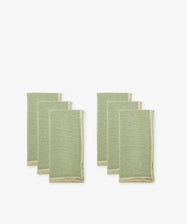 Set of six Corte Napkins in green linen with beige edging, eco-friendly, folded and arranged in two groups on a white background.