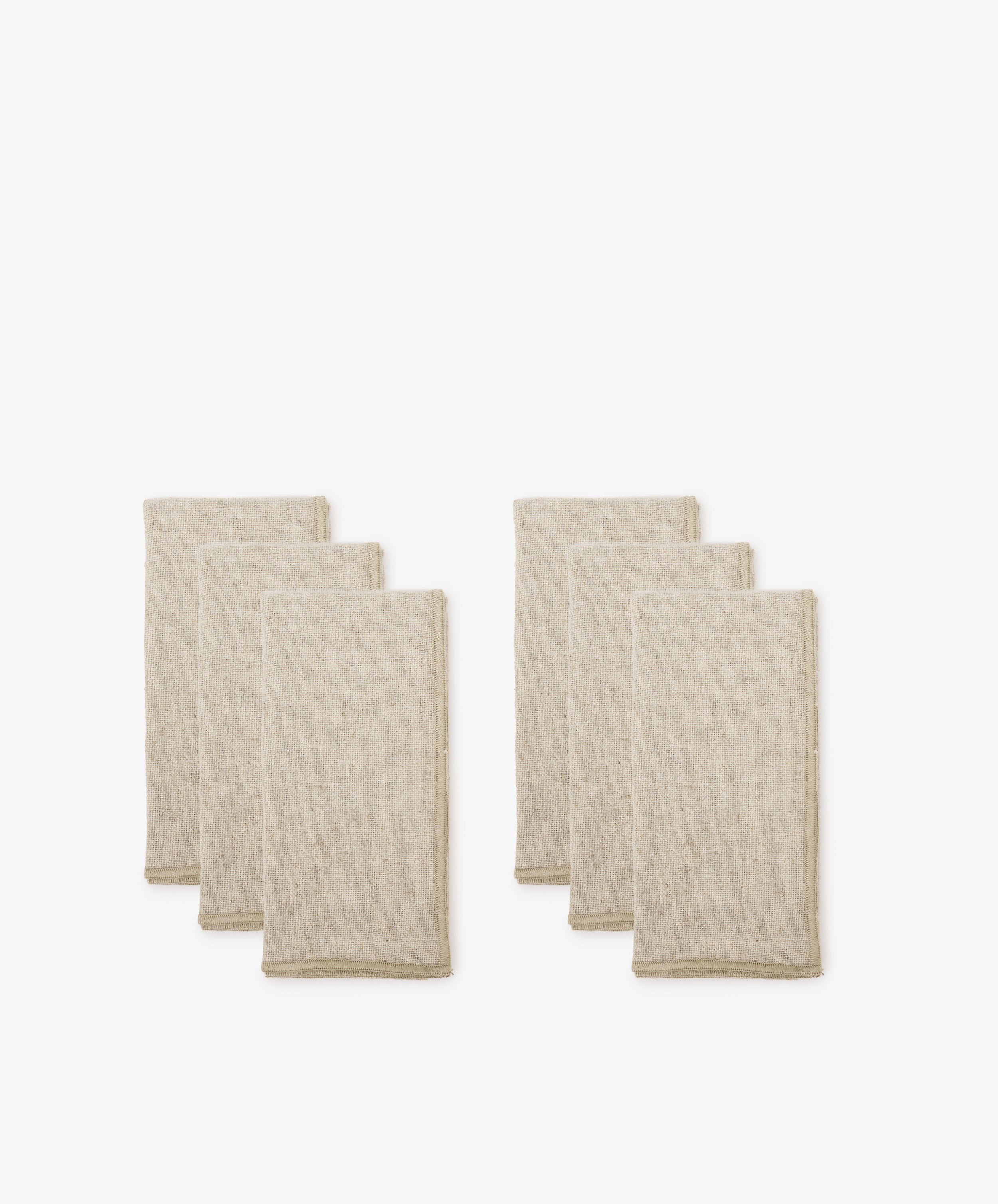 A set of six beige Corte Napkins, neatly folded and eco-friendly, is arranged in two groups against a plain white background.