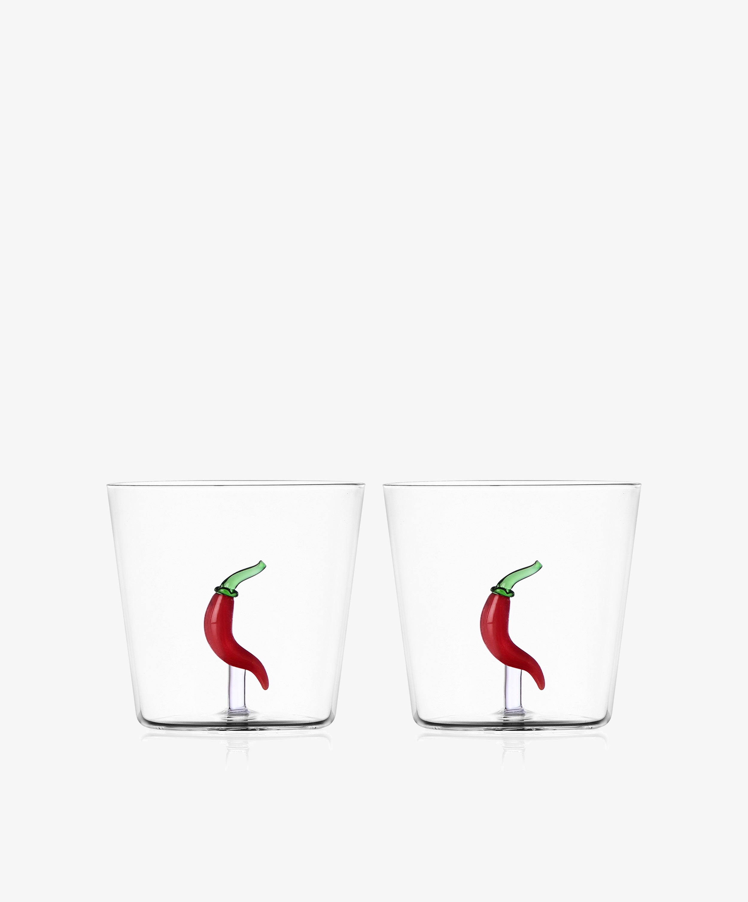 The Chili Pepper Tumbler, Set of 2, includes clear handcrafted borosilicate glass tumblers with a small red chili pepper design embedded at the bottom.