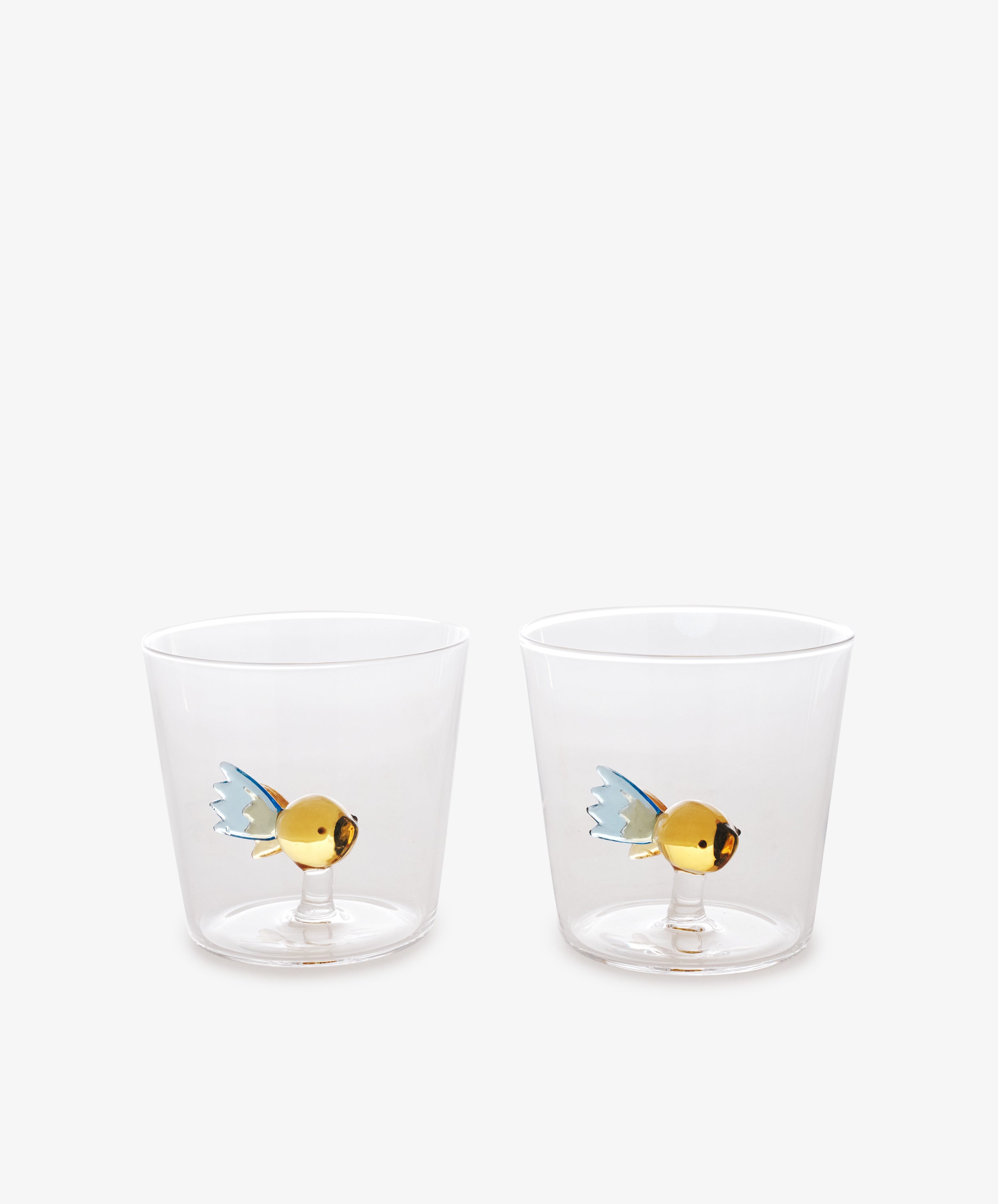 The Fish Tumbler, Set of 2, crafted from borosilicate glass with gold and blue fish designs inside, are displayed side by side on a plain white background.