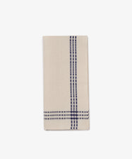 The Tilde Tea Towel, made from a beige cotton-linen blend, features two navy blue plaid stripes running vertically and horizontally near the edge and is shown folded on a white background.