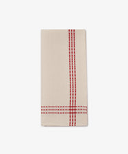 The Tilde Tea Towel, crafted from a cotton and linen blend in the traditional Daldräll pattern, features beige fabric with red plaid stripes along one edge, and is neatly folded on a white background.
