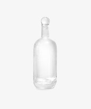 The Bubble Glass Carafe, crafted from clear hand-blown glass and topped with a round stopper, is showcased against a plain white background.
