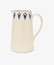 The Vito Jug is a cream ceramic jug with a handle, featuring blue geometric patterns near the rim. Handmade and unique, it makes a thoughtful gift and is displayed against a simple white background.