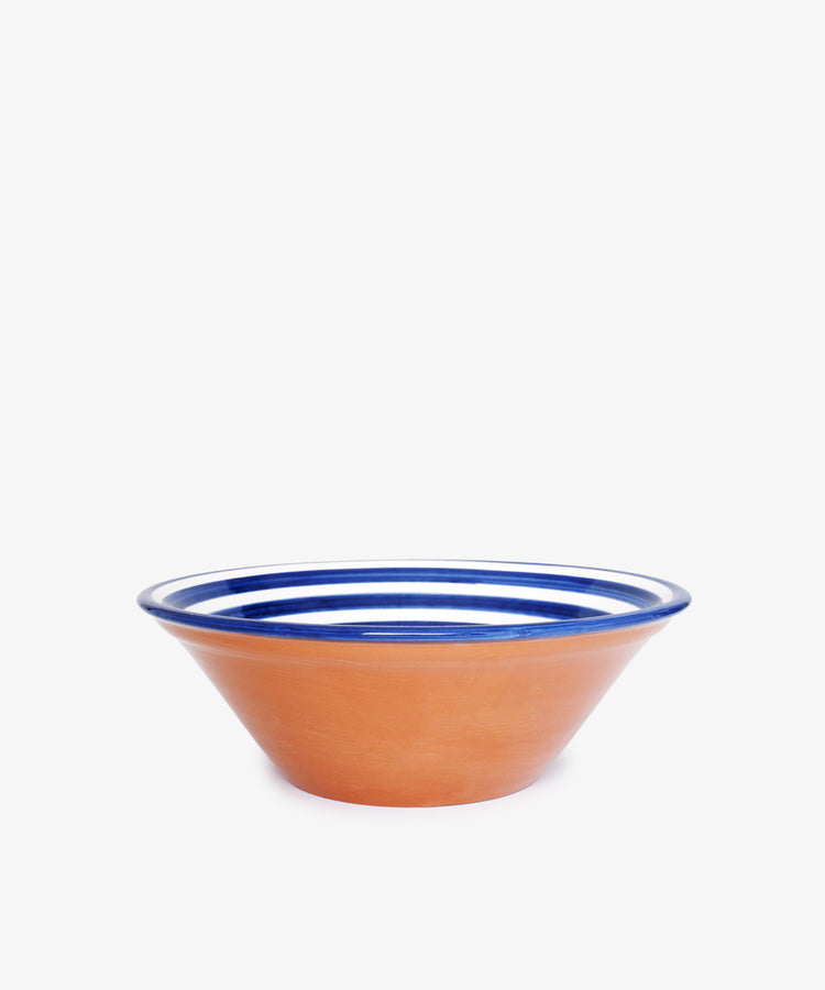 The Natalia Serving Bowl is a unique, handmade terracotta piece with a wide rim, showcasing blue and white concentric stripes near the top, displayed against a plain white background.