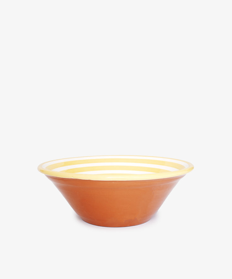 The Natalia Serving Bowl is a unique, handmade ceramic piece featuring a reddish-brown exterior and a yellow and white striped interior, shown on a plain white background.