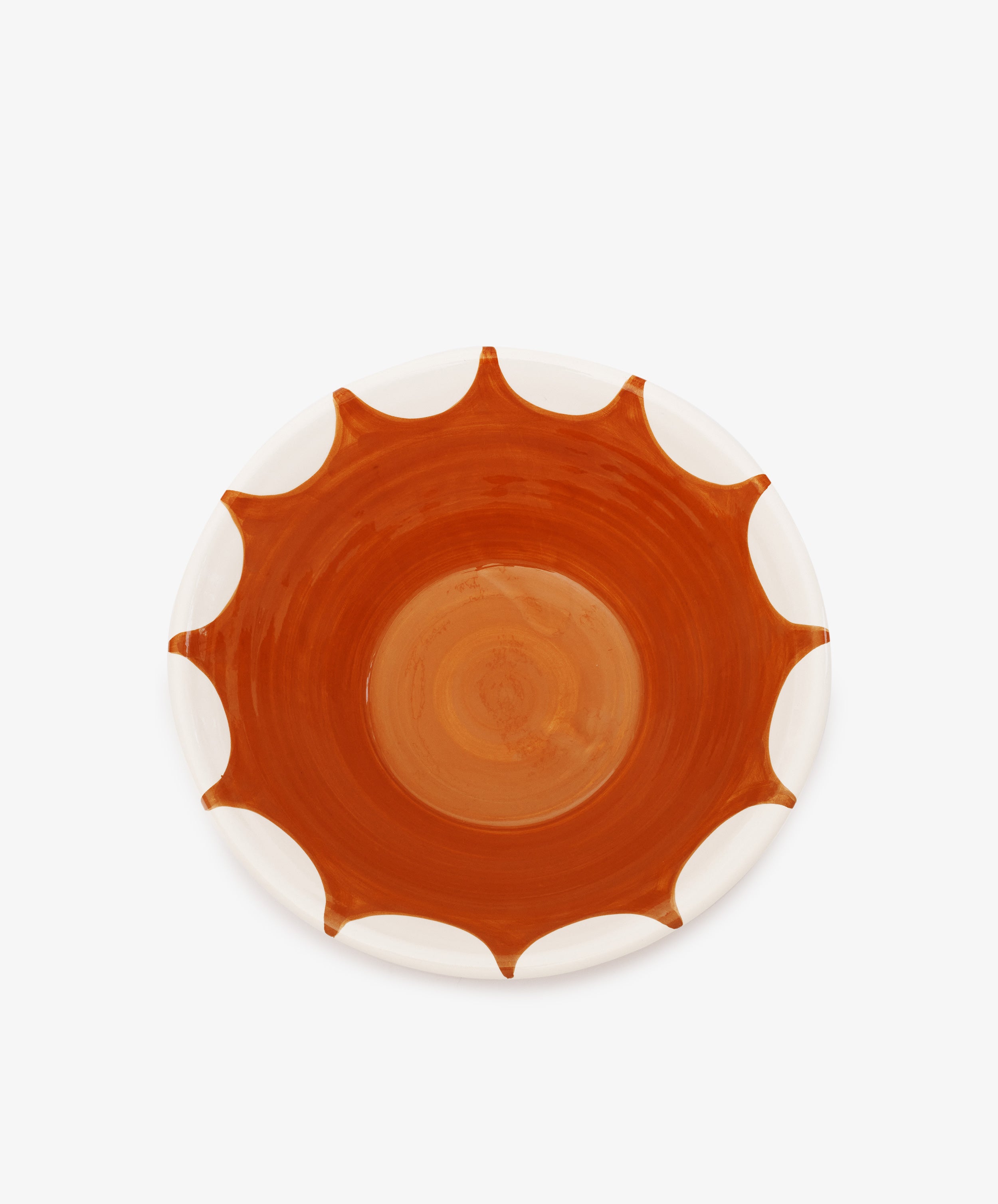 The Stella Serving Bowl is a round, handmade ceramic bowl featuring a white rim and a central orange-brown sunburst pattern, shown against a plain white background.